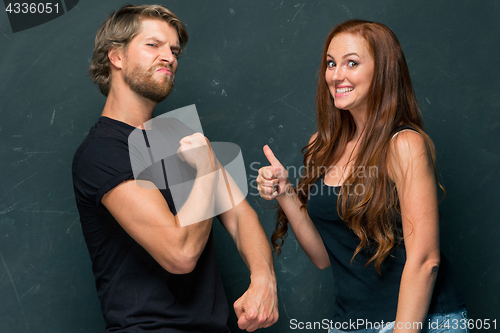 Image of Beautiful woman impressed by the muscles of a bodybuilder, strong man showing off his muscles