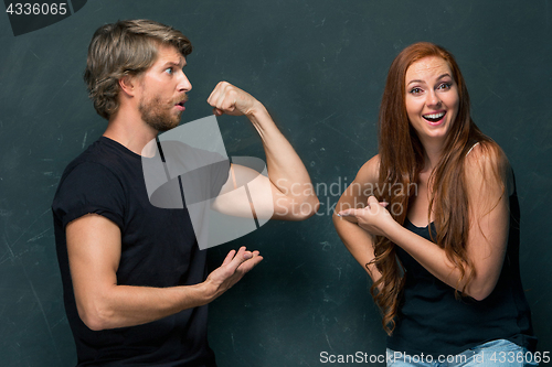 Image of Beautiful woman impressed by the muscles of a bodybuilder, strong man showing off his muscles