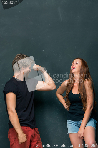 Image of Beautiful woman impressed by the muscles of a bodybuilder, strong man showing off his muscles