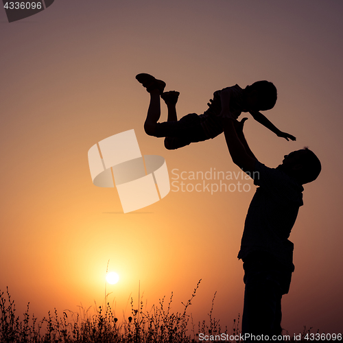 Image of Father and son playing in the park at the sunset time.