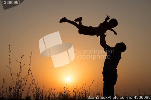 Image of Father and son playing in the park at the sunset time.