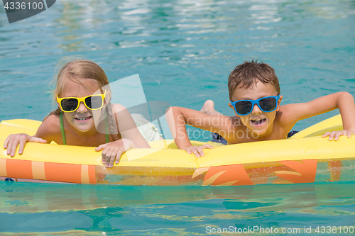 Image of Two happy children playing on the swimming pool at the day time.