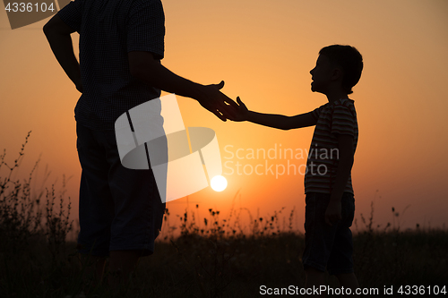 Image of Father and son playing in the park at the sunset time.