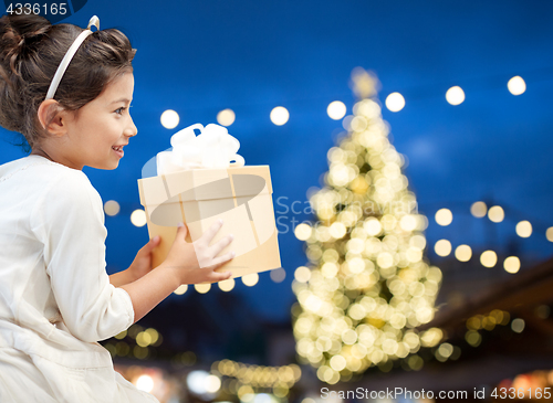 Image of happy girl with gift box over christmas lights