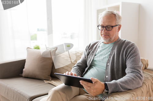 Image of senior man with tablet pc sitting on sofa at home