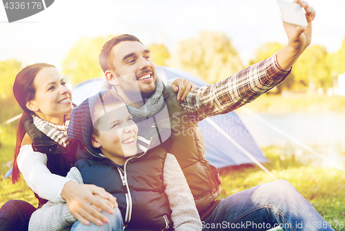 Image of family with smartphone taking selfie at campsite