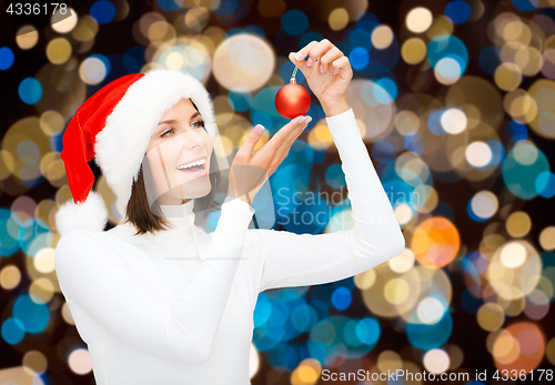 Image of happy woman in santa hat with christmas ball