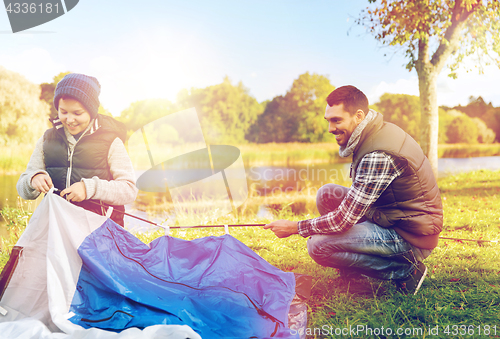 Image of happy father and son setting up tent outdoors