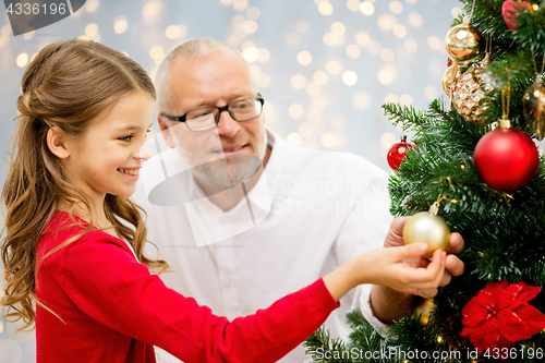Image of grandfather and granddaughter at christmas tree