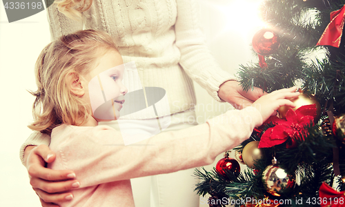 Image of happy family decorating christmas tree at home