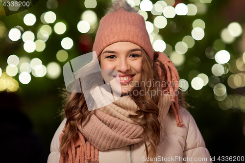 Image of happy young woman over christmas tree lights