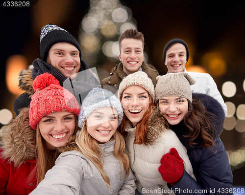 Image of happy friends taking selfie outdoors at christmas