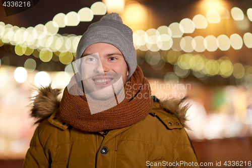 Image of happy young man over christmas lights in winter