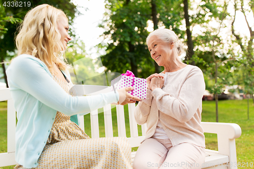 Image of daughter giving present to senior mother at park