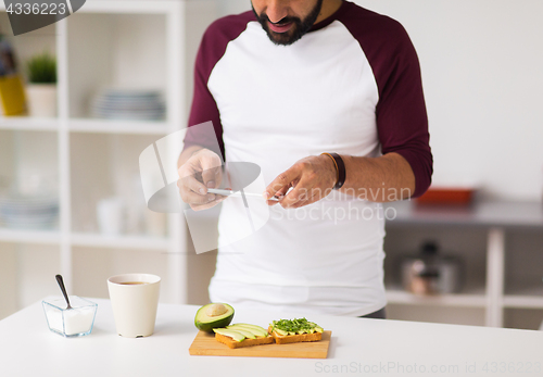 Image of man photographing food by smartphone at home