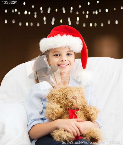 Image of girl in santa hat with teddy bear at christmas