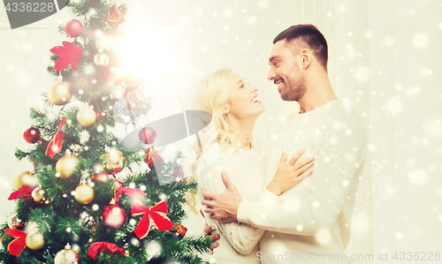 Image of happy couple hugging near christmas tree at home