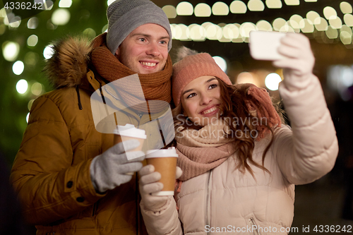 Image of couple with coffee taking selfie at christmas