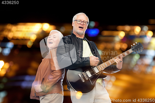 Image of happy senior couple with electric guitar singing