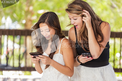 Image of Two Expressive Mixed Race Girlfriends Using Their Smart Cell Pho