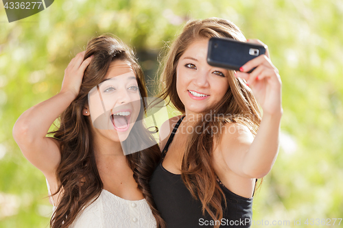 Image of Two Attractive Mixed Race Girlfriends Using Their Smart Cell Pho