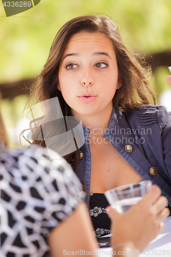 Image of Expressive Young Adult Woman Having Drinks and Talking with Her 