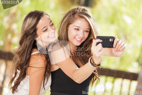Image of Two Attractive Mixed Race Girlfriends Using Their Smart Cell Pho