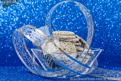 Image of Colored chocolate rings in bowl with Christmas decoration on blu