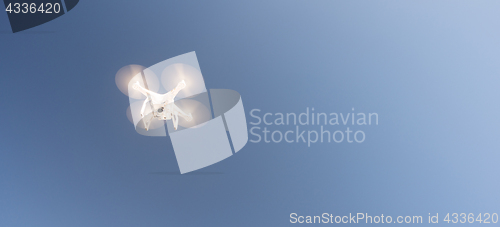 Image of White UAV Quadcopter Drone in Flight Blue Sky