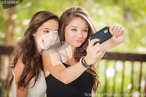 Image of Two Attractive Mixed Race Girlfriends Using Their Smart Cell Pho