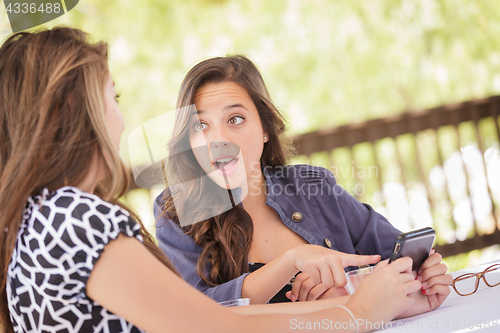 Image of Expressive Young Adult Girlfriends Using Their Smart Cell Phone 