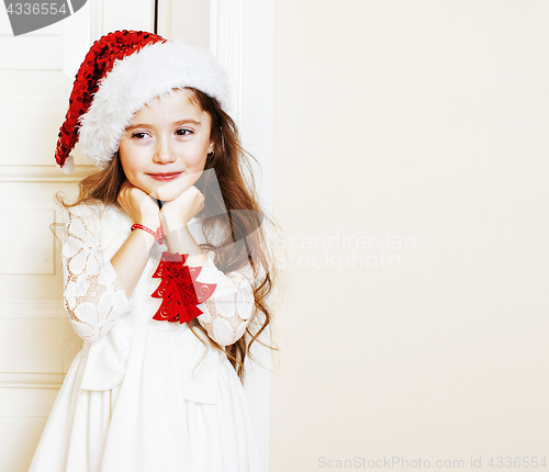 Image of little cute girl in santas red hat waiting for Christmas gifts. 