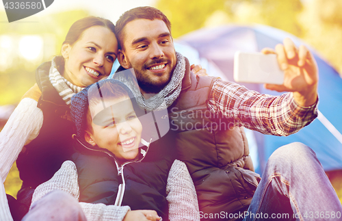 Image of family with smartphone taking selfie at campsite