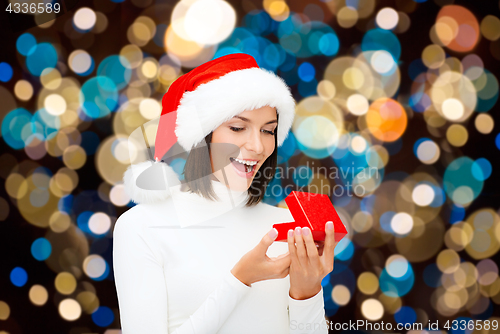 Image of happy woman in santa hat opening christmas gift