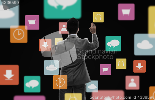 Image of businessman working with virtual icons over black