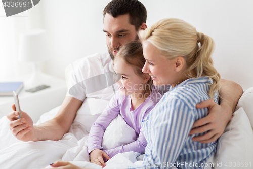 Image of happy family taking selfie by smartphone at home