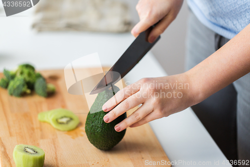 Image of woman hands chopping avocado on cutting board