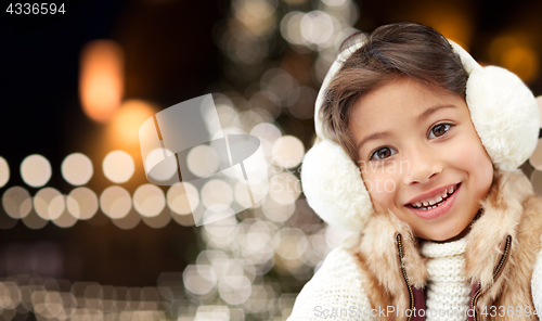 Image of happy girl wearing earmuffs over christmas lights