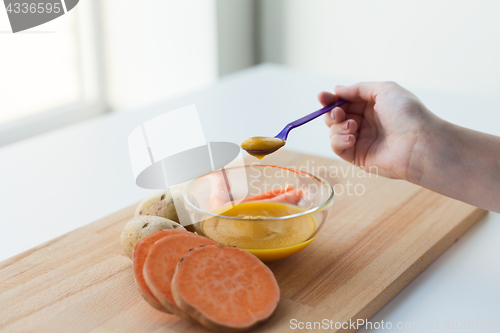 Image of hand with vegetable puree or baby food in spoon