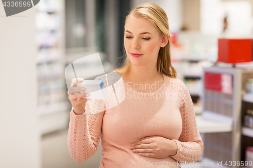 Image of happy pregnant woman with medication at pharmacy