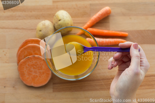 Image of hand with vegetable puree or baby food in spoon