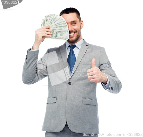 Image of smiling businessman with money showing thumbs up