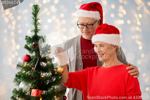 Image of happy senior couple decorating christmas tree