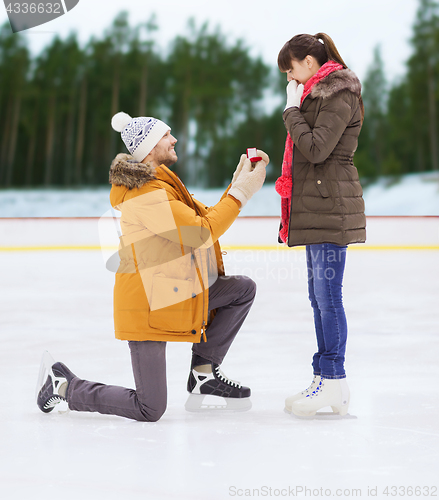 Image of happy couple with engagement ring on skating rink