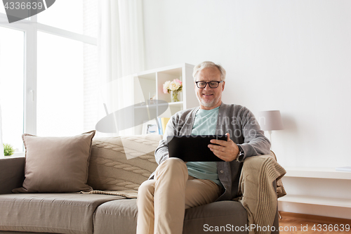 Image of senior man with tablet pc sitting on sofa at home