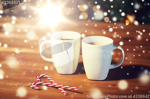 Image of christmas candy canes and cups on wooden table