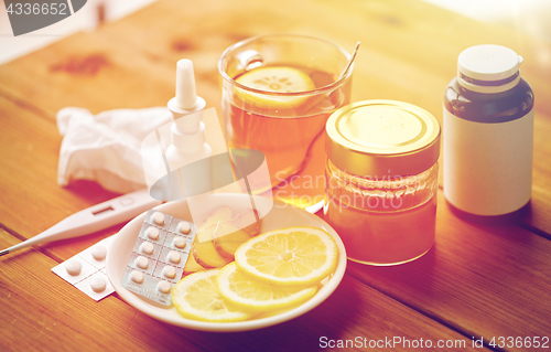 Image of drugs, thermometer, honey and cup of tea on wood