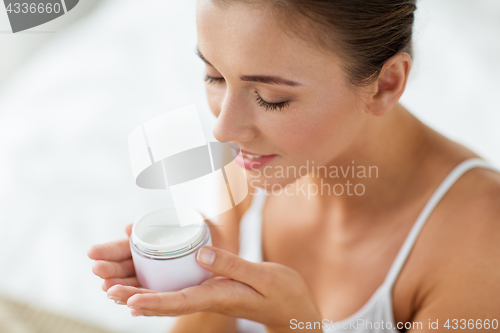 Image of close up of happy woman holding and smelling cream