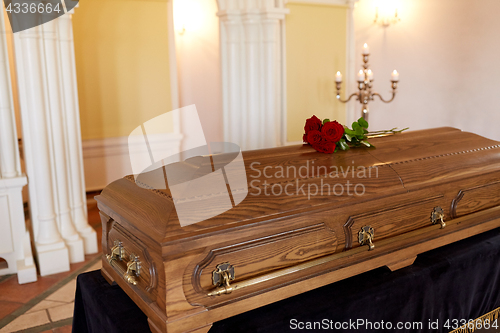 Image of red rose flowers on wooden coffin in church