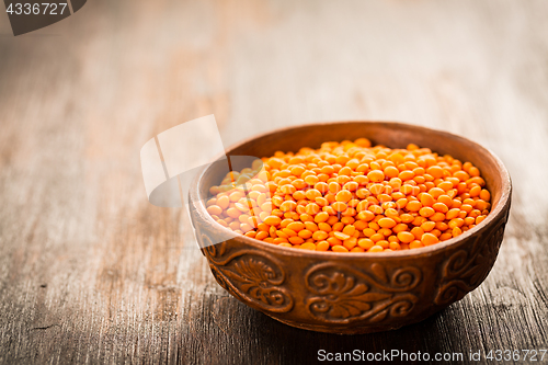 Image of Red lentils in a bowl on old wooden table